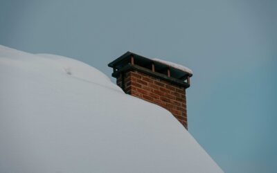 Brick chimney on a snow-covered roof, illustrating freeze-thaw chimney damage in Indiana