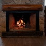 Stone fireplace with a roaring fire, illustrating correct fireplace damper use
