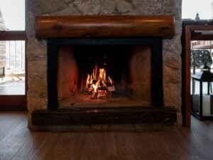 Stone fireplace with a roaring fire, illustrating correct fireplace damper use